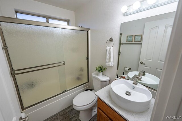 full bathroom with toilet, combined bath / shower with glass door, and vanity