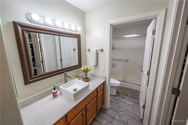 full bath with toilet, an enclosed shower, wood finished floors, and vanity