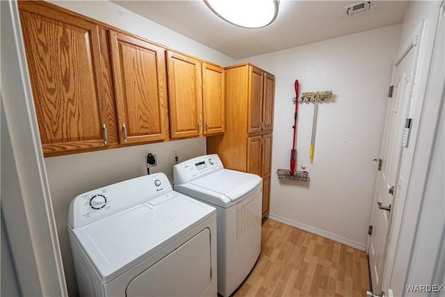laundry area with visible vents, baseboards, light wood-style floors, cabinet space, and washer and clothes dryer
