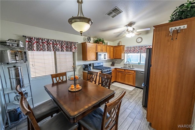 dining room with visible vents, ceiling fan, vaulted ceiling, and wood tiled floor
