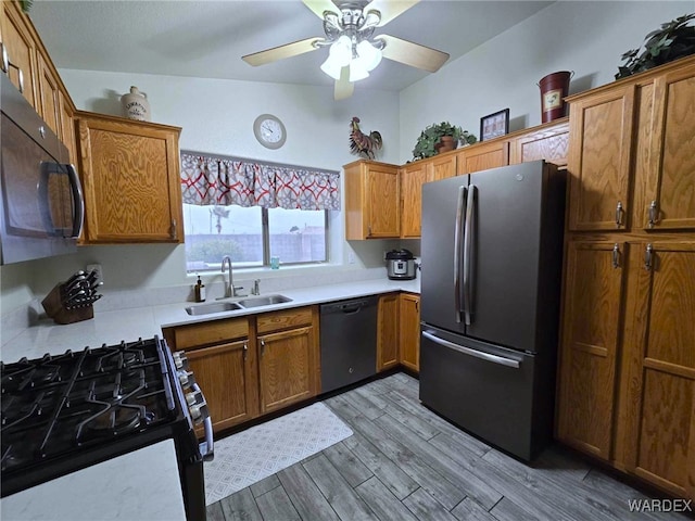 kitchen with dishwashing machine, freestanding refrigerator, a sink, light wood-style floors, and black microwave