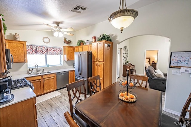 kitchen with arched walkways, a ceiling fan, visible vents, a sink, and stainless steel appliances