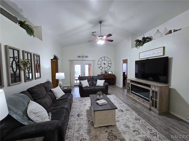 living area with wood finished floors, baseboards, high vaulted ceiling, ceiling fan, and french doors