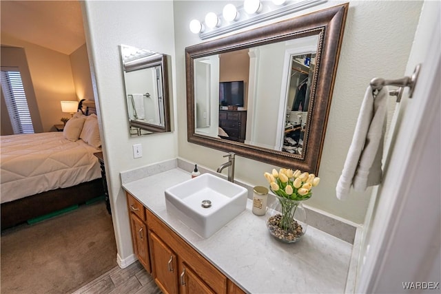 bathroom with vanity, ensuite bathroom, and wood finished floors