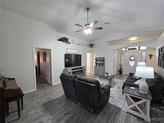 living room with a ceiling fan, wood finished floors, visible vents, arched walkways, and vaulted ceiling