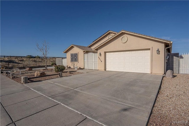 ranch-style home with driveway, stucco siding, and a gate