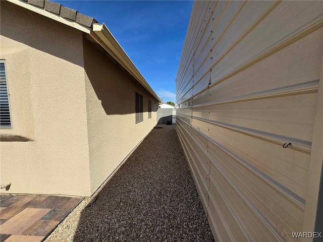 view of side of home with stucco siding and fence