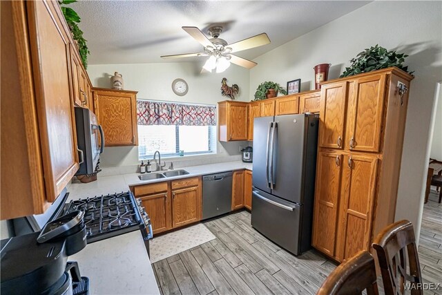 kitchen featuring light wood-style floors, ceiling fan, appliances with stainless steel finishes, light countertops, and a sink