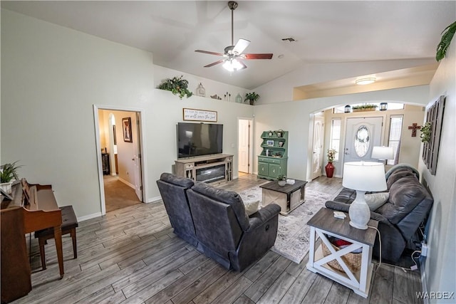 living area with baseboards, arched walkways, a ceiling fan, wood finished floors, and lofted ceiling