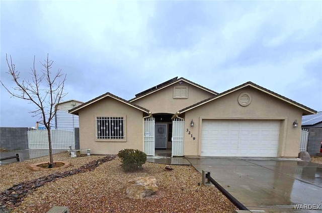 ranch-style house featuring stucco siding, driveway, an attached garage, and fence