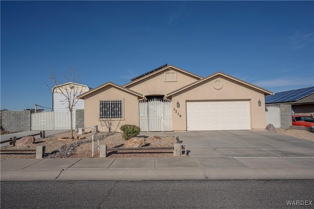 view of front of house with stucco siding, driveway, a fenced front yard, a garage, and a gate