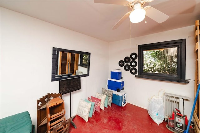 living area featuring radiator, concrete floors, a ceiling fan, and baseboards