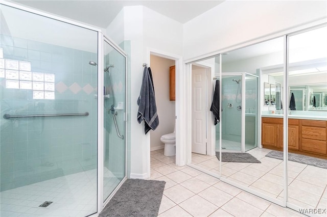 bathroom with tile patterned flooring, baseboards, toilet, a stall shower, and vanity