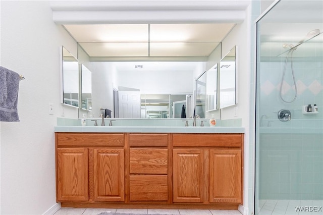 bathroom featuring double vanity, a stall shower, and a sink