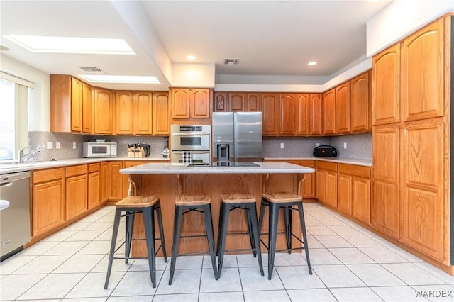 kitchen featuring a sink, a kitchen breakfast bar, visible vents, and stainless steel appliances