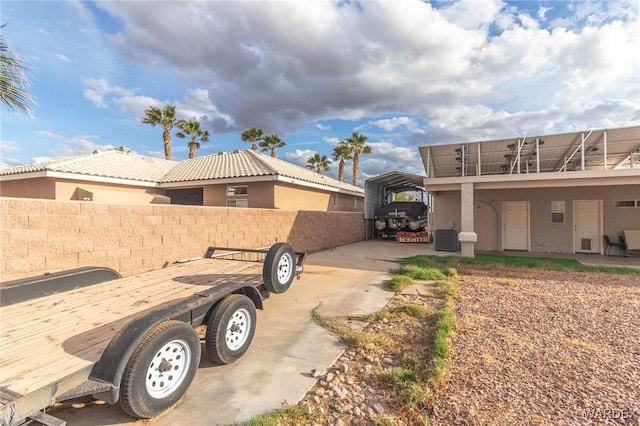 view of side of property with a carport, fence, and stucco siding