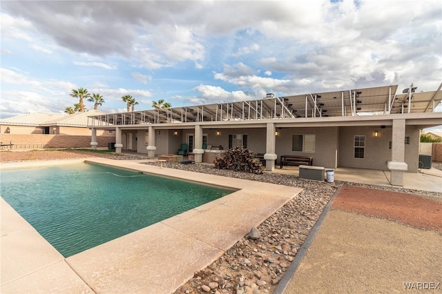 rear view of house featuring stucco siding, a patio, and a fenced in pool