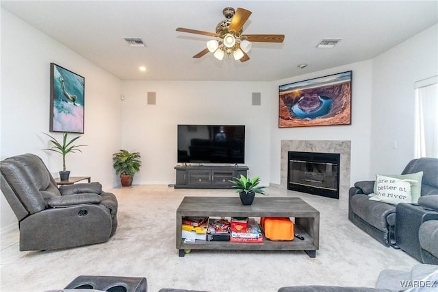 living room with a high end fireplace, visible vents, carpet, and a ceiling fan