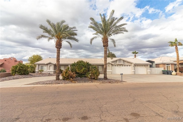 view of front of property featuring stucco siding, driveway, a tile roof, and a garage