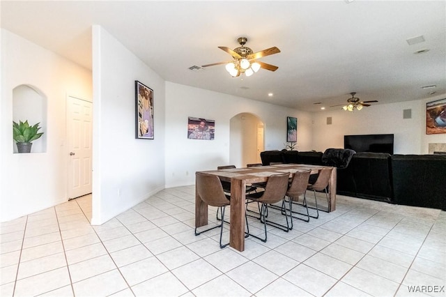 dining space with light tile patterned floors, visible vents, arched walkways, and ceiling fan