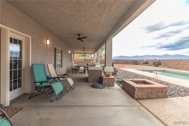 view of patio with an outdoor pool, a mountain view, and ceiling fan