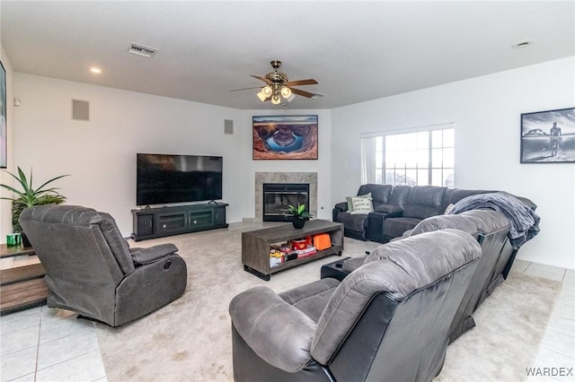 living area featuring light tile patterned flooring, visible vents, and ceiling fan