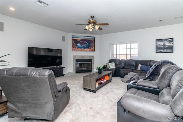 living room featuring light carpet, visible vents, ceiling fan, and a high end fireplace