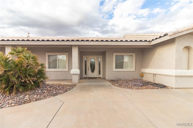 entrance to property featuring stucco siding and a tile roof