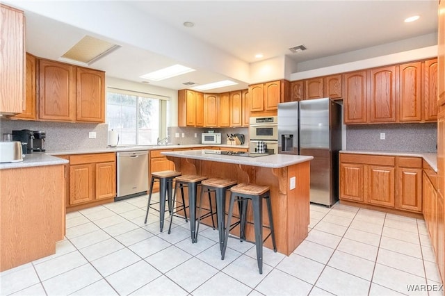 kitchen featuring a breakfast bar area, visible vents, a kitchen island, appliances with stainless steel finishes, and tasteful backsplash