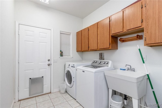 washroom featuring independent washer and dryer, a sink, cabinet space, light tile patterned flooring, and baseboards