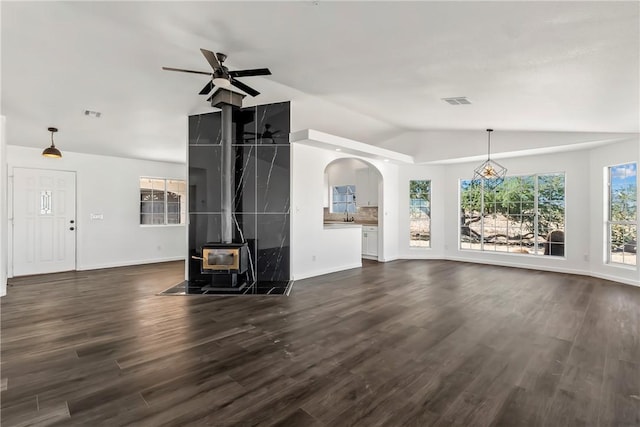 15565 Iron Dr, Dolan Springs, AZ 86441 - unfurnished living room with vaulted ceiling, a wood stove, a ceiling fan, dark wood-style flooring, and arched walkways