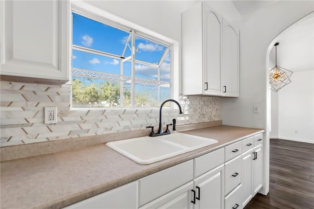 15565 Iron Dr, Dolan Springs, AZ 86441 - kitchen with white cabinetry, tasteful backsplash, dark wood finished floors, light countertops, and arched walkways