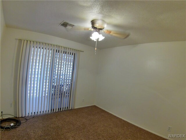 spare room with a textured ceiling, ceiling fan, carpet, and visible vents