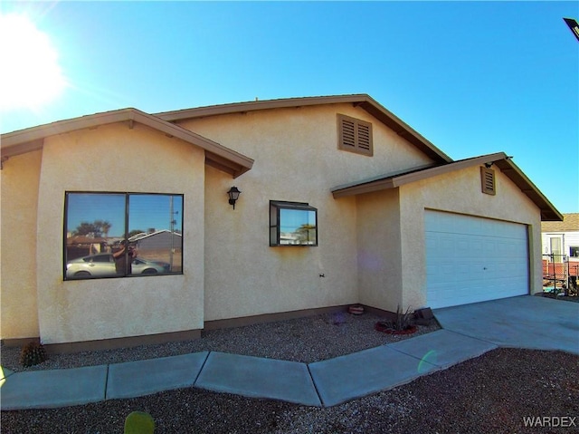 exterior space with driveway, an attached garage, and stucco siding