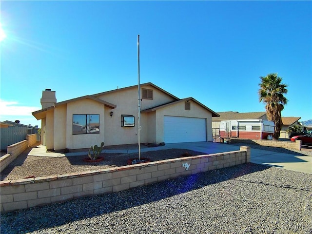 view of front facade featuring a garage, concrete driveway, a chimney, fence, and stucco siding