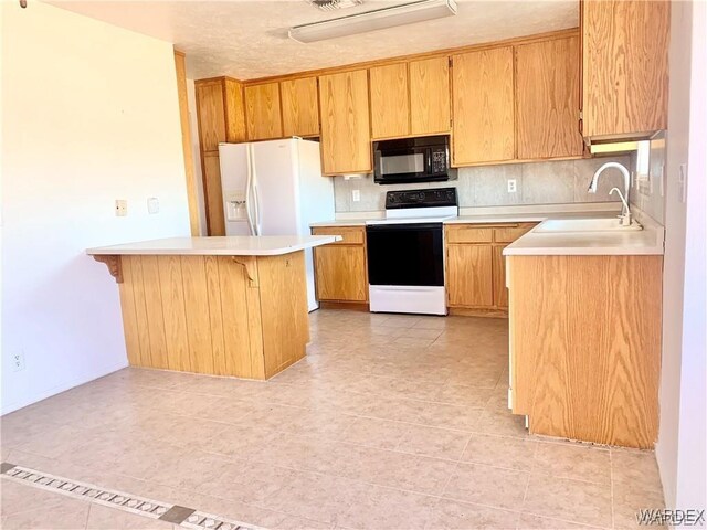 kitchen featuring white appliances, a breakfast bar, a sink, light countertops, and brown cabinets