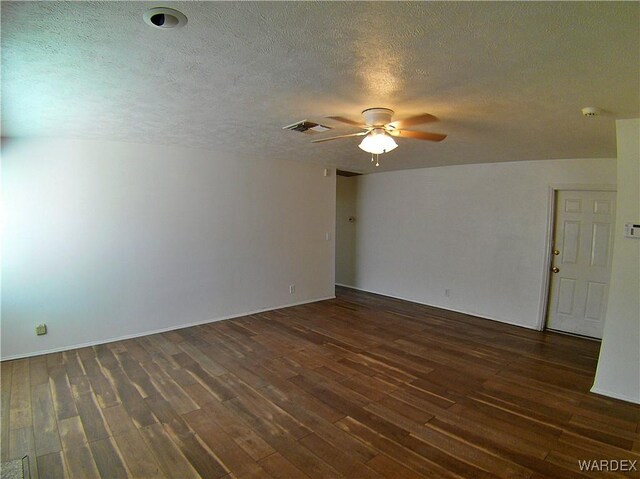 spare room with dark wood-style floors, ceiling fan, visible vents, and a textured ceiling