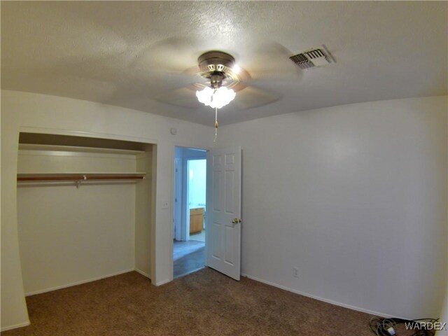 unfurnished bedroom featuring visible vents, ceiling fan, carpet, a textured ceiling, and a closet