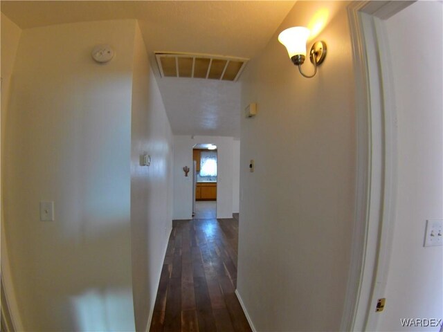 hall with arched walkways, dark wood finished floors, and visible vents