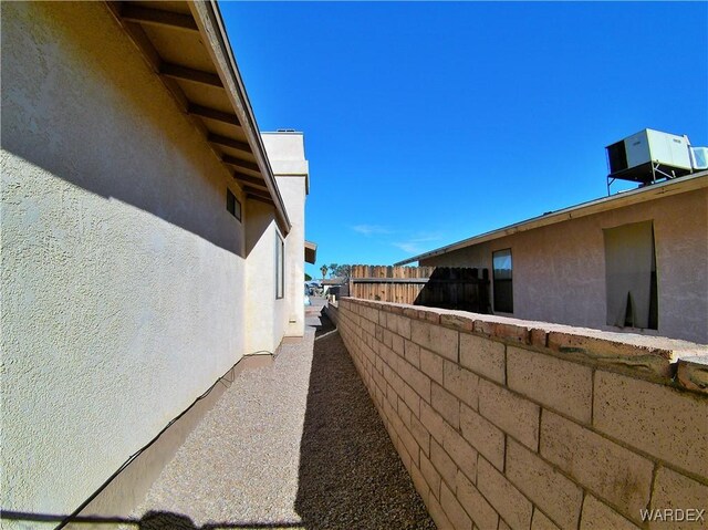 view of side of home featuring central air condition unit, fence, and stucco siding