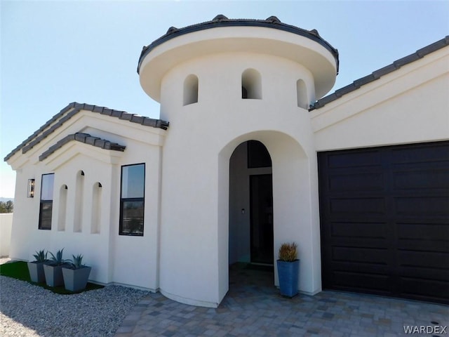 view of front of home featuring a garage, a tile roof, and stucco siding