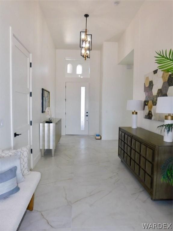 foyer entrance featuring a chandelier and marble finish floor