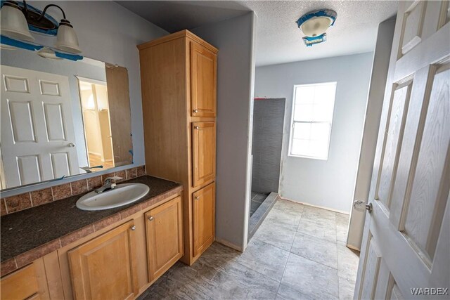 full bathroom with backsplash, a textured ceiling, vanity, tile patterned flooring, and walk in shower