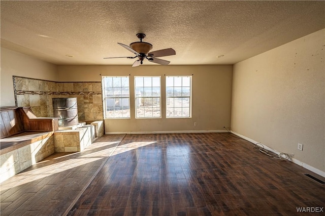 unfurnished living room featuring a textured ceiling, ceiling fan, wood finished floors, and visible vents