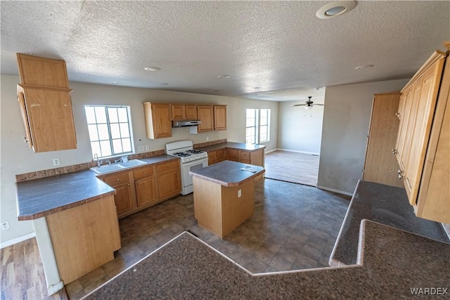 kitchen featuring under cabinet range hood, a kitchen island, open floor plan, white gas range, and dark countertops