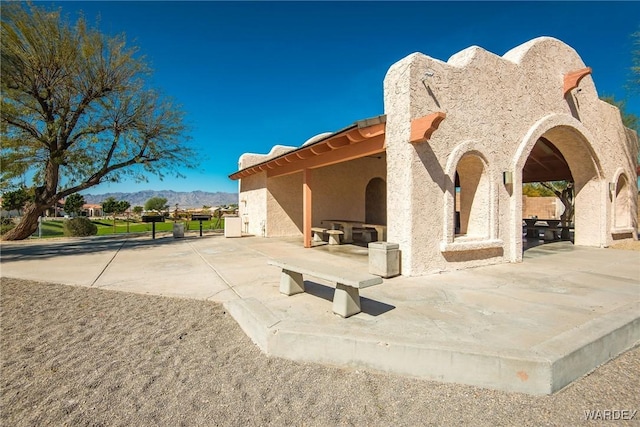 exterior space featuring a patio area, a mountain view, and stucco siding