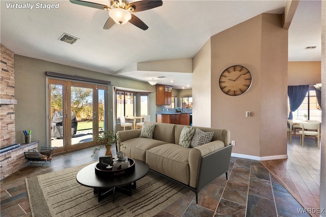 living room with lofted ceiling, a ceiling fan, visible vents, and baseboards