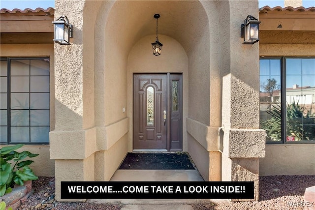 entrance to property with a tile roof and stucco siding