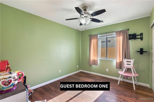 recreation room featuring dark wood-type flooring, a ceiling fan, and baseboards