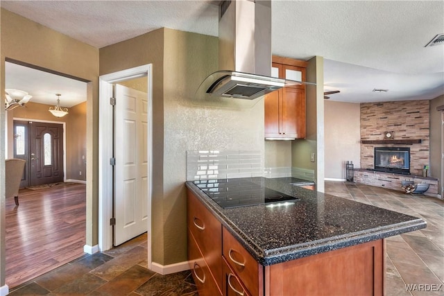 kitchen with brown cabinets, a fireplace, island exhaust hood, baseboards, and black electric cooktop